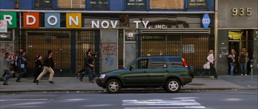 Sue running along a New York sidewalk, followed by people.