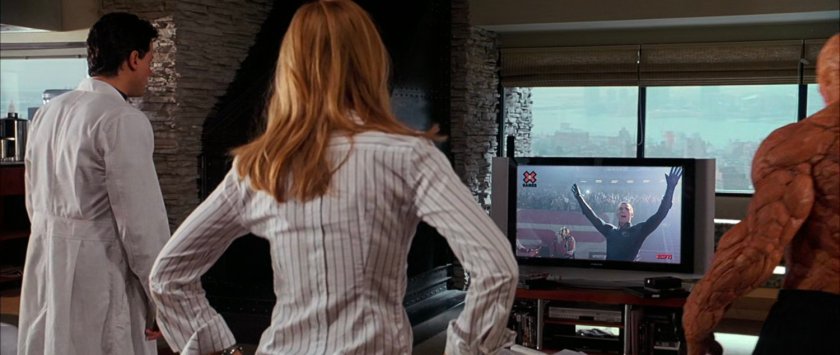 Sue, Reed, and Ben in the living room of the Baxter Building, watching Johnny on TV..