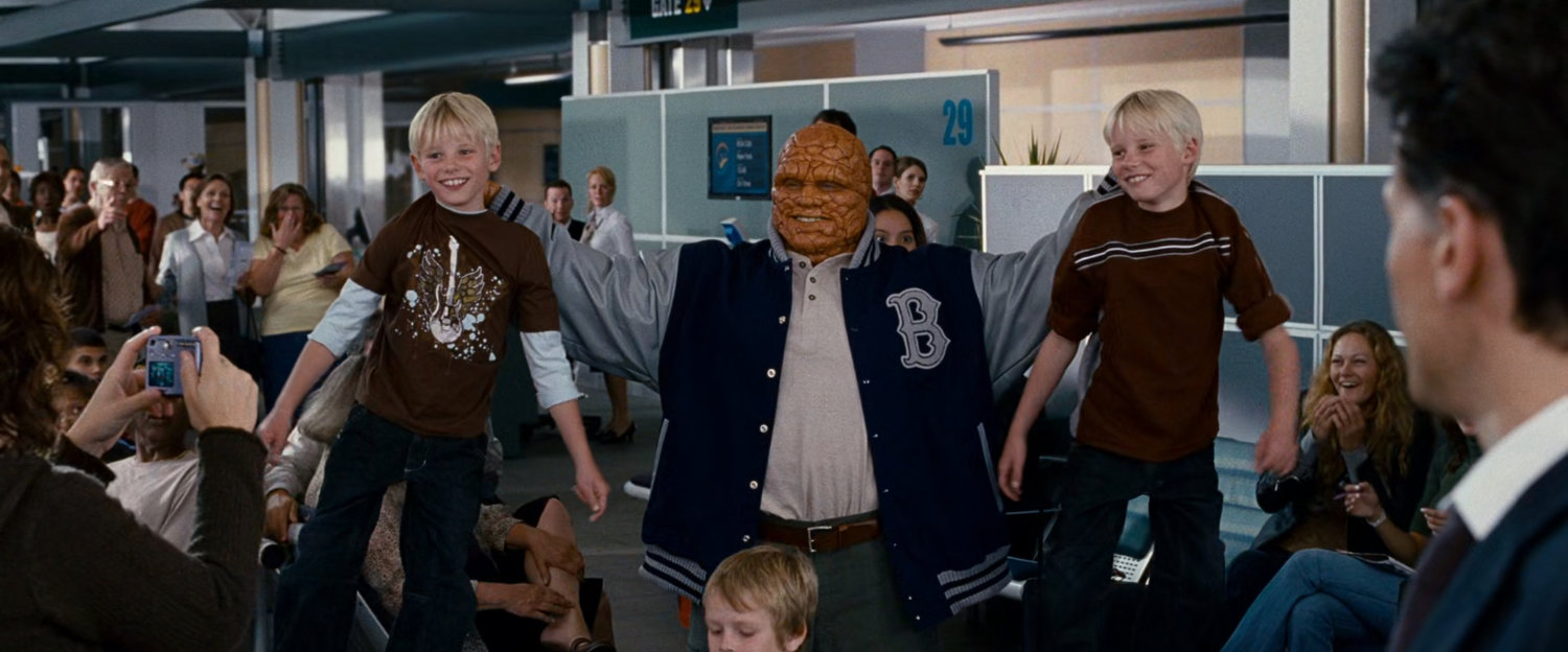 The Thing lifting two young boys by their shirts in an airport.