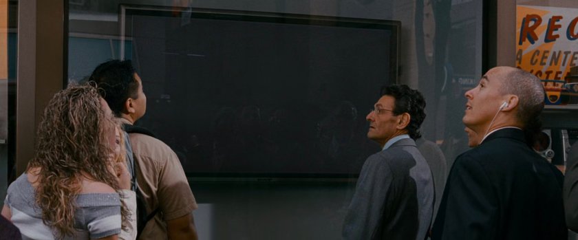 Pedestrians in front of a TV store display.