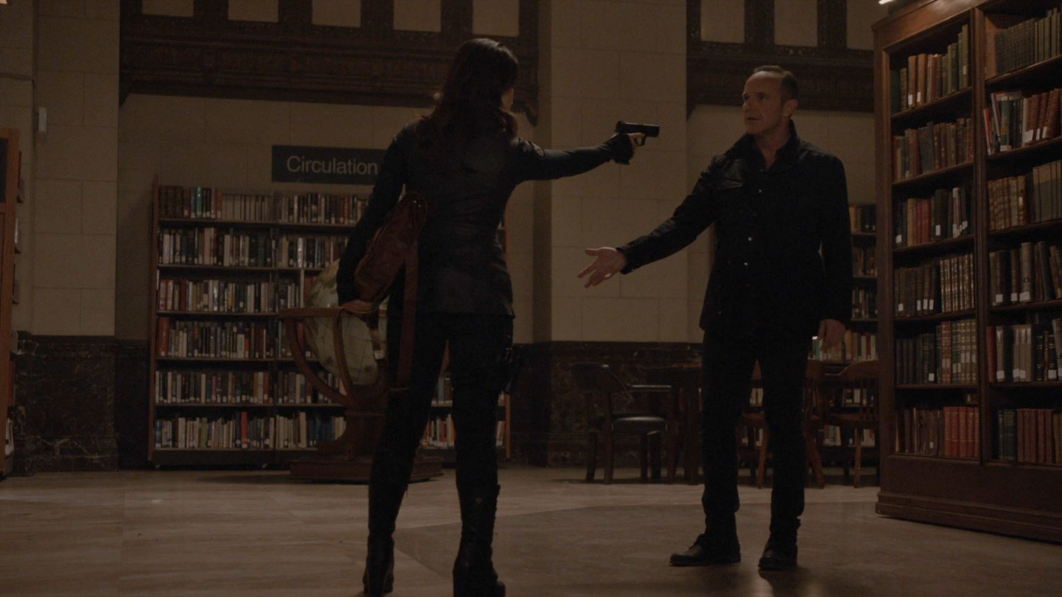 May-bot holds a gun on Coulson in the Pleasant Hill Public Library.