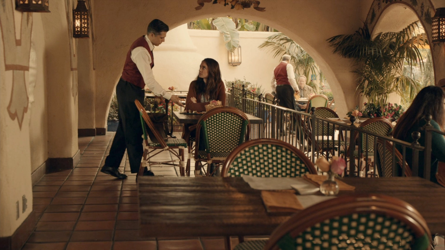 Agnes and a waiter at a cafe in a Spanish plaza.