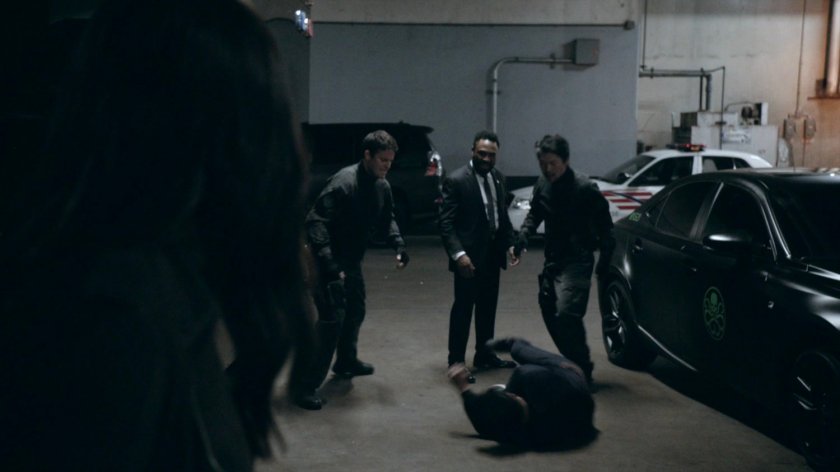 Three men beating another man in the garage of Framework Triskelion.