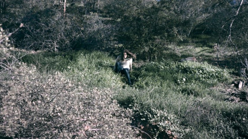 Simmons slides down a brush-strewn hill on the SHIELD academy grounds in the Framework.
