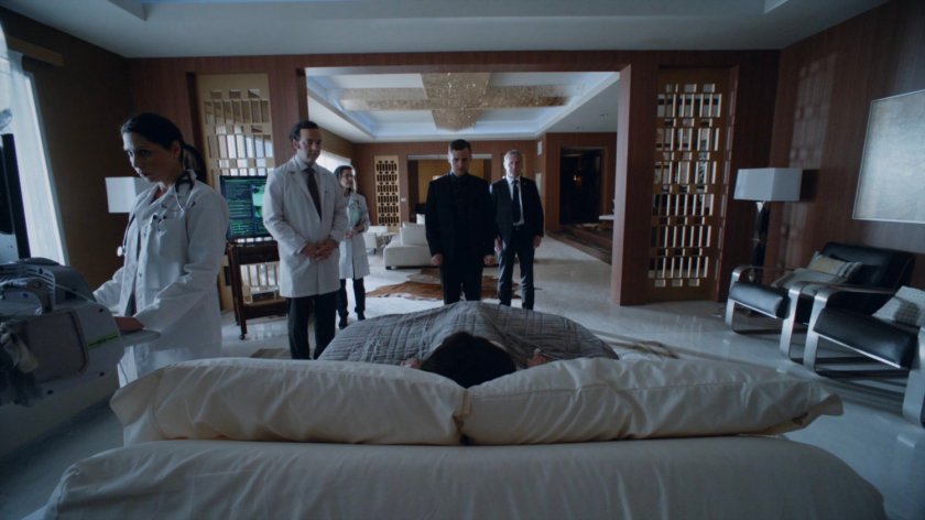Fitz and doctors stand around a bedridden Madame Hydra in her apartment in the Framework.