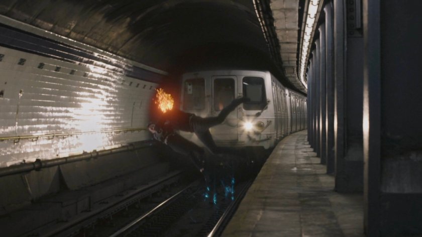 Aida and Ghost Rider fighting in front of a subway train in a tunnel.