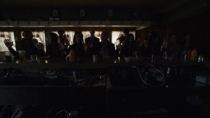 The Agents of SHIELD sitting at a counter in a diner in the dark.