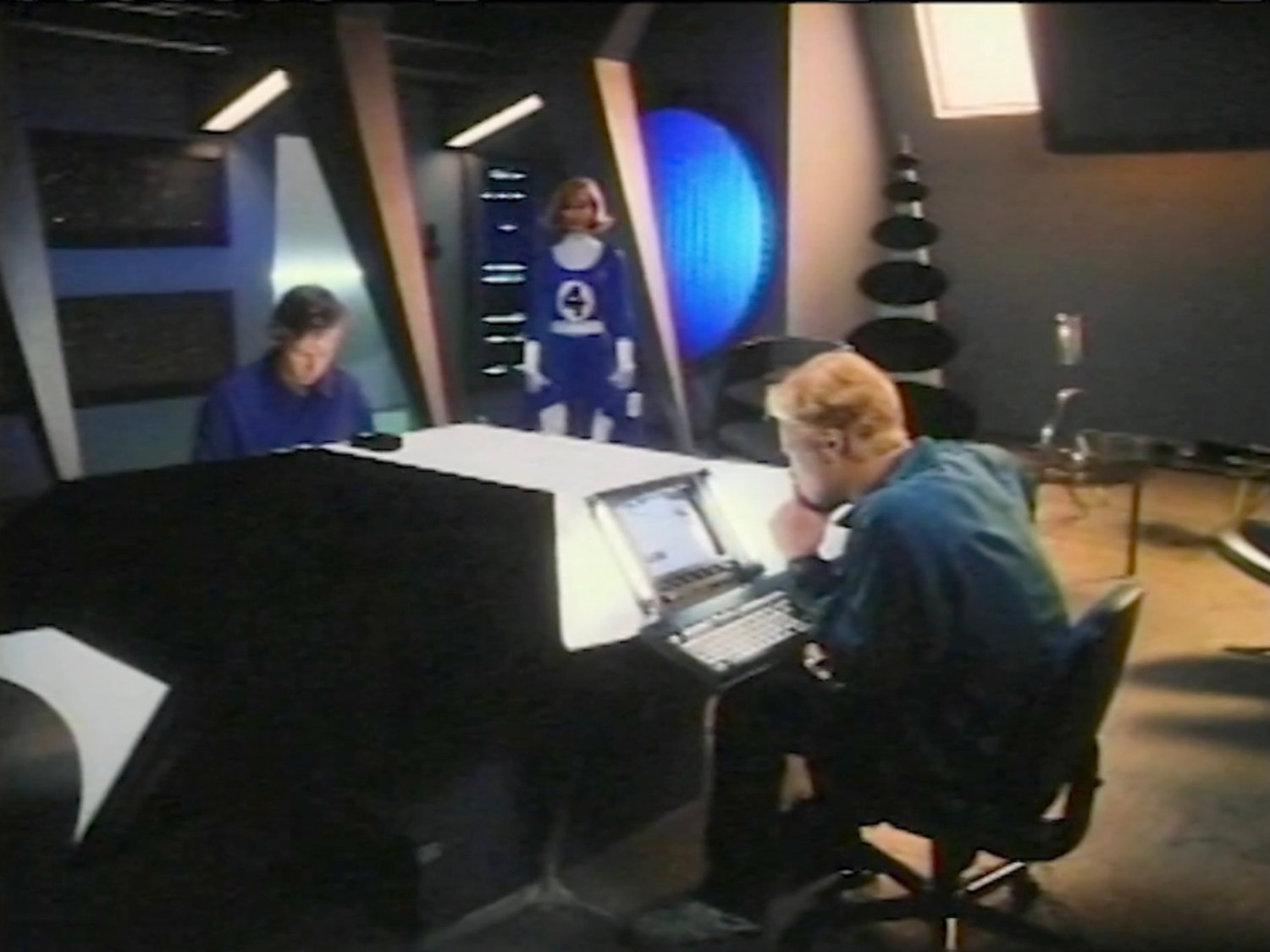 Reed and Johnny in the Baxter Building lab, with Sue entering in costume.