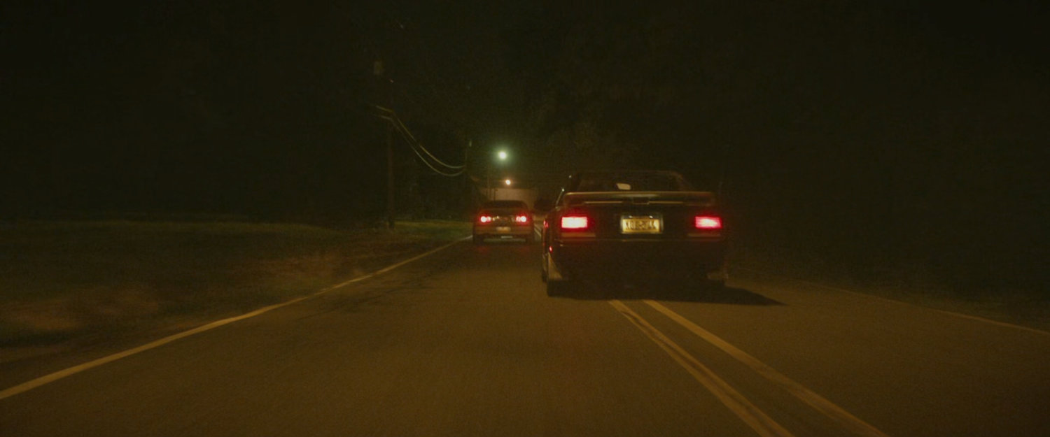 Two cars racing on a small street.