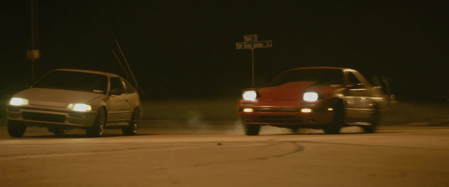 Two cars racing on a street.