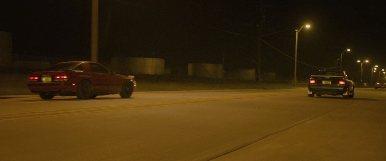 Two cars racing on a street.