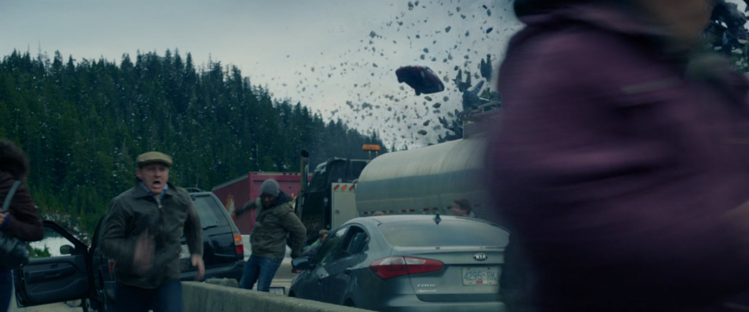 People running from their cars as rocks fly past them.
