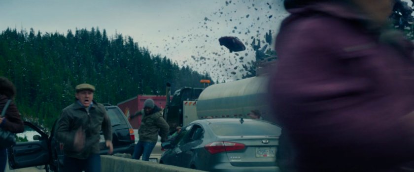People running from their cars as rocks fly past them.