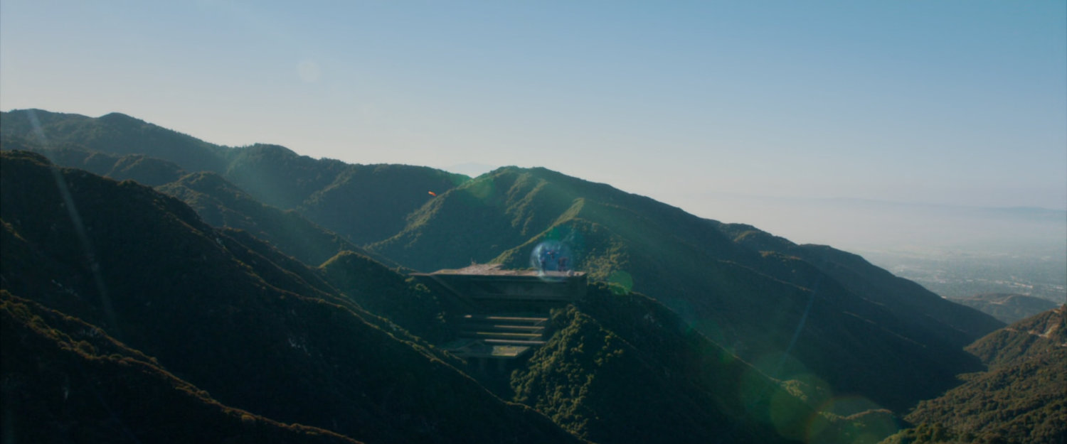 The Human Torch flies over forested hills towards Central City.