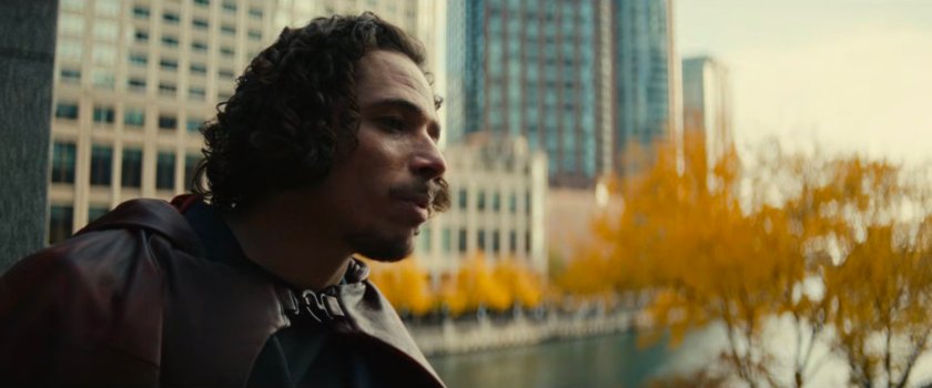 The Hood leaning on a railing by the river.