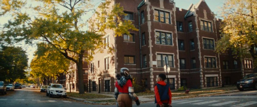 Landon and Riri walking along a street towards Riri's apartment building.