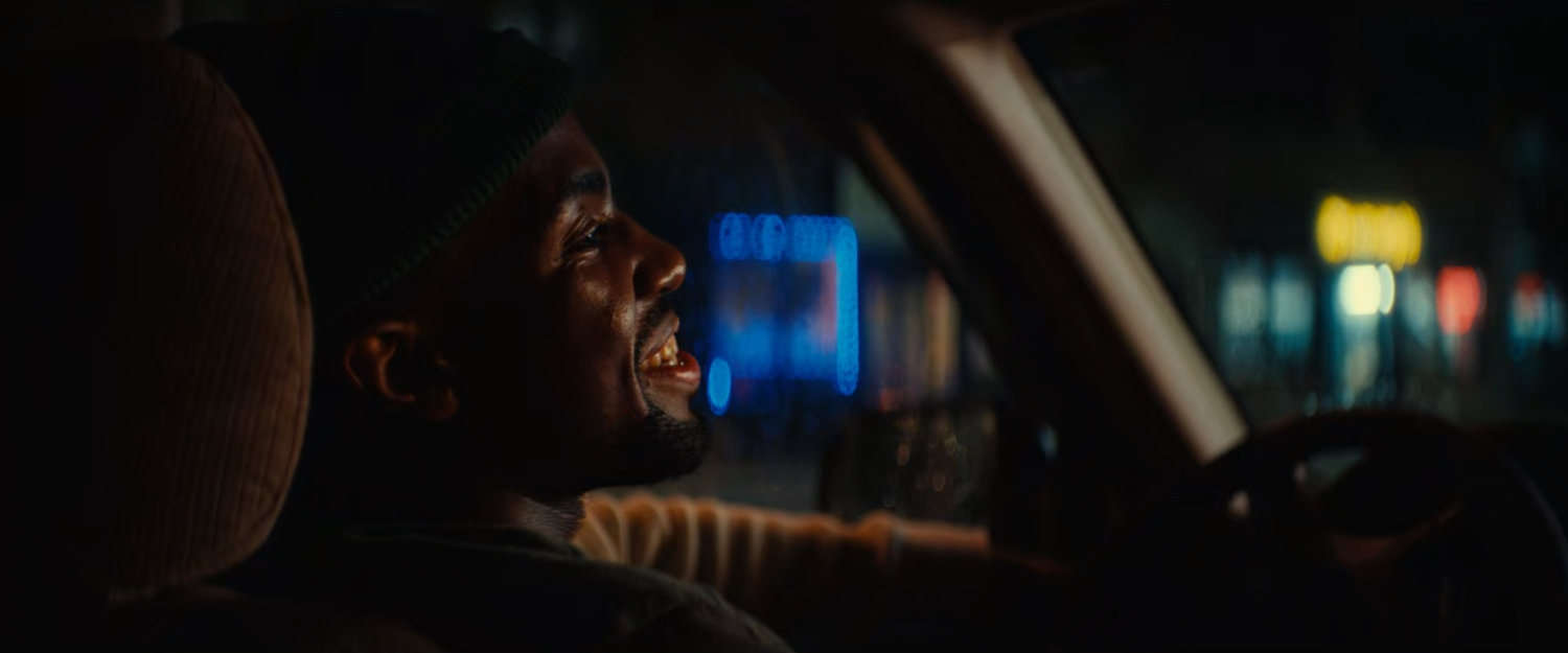 Xavier in a car outside Gary's Auto Repair.
