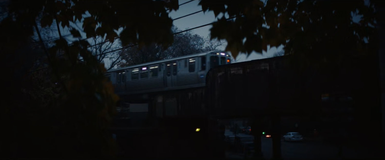 An L train passing over a bridge at dusk.