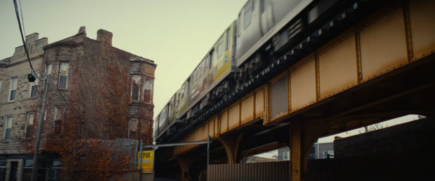 L Train passing by a brick building.