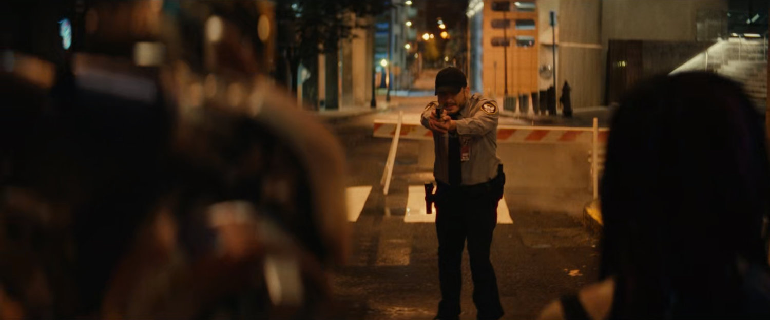 A police officer draws his weapon on Riri on the street above TNNL.