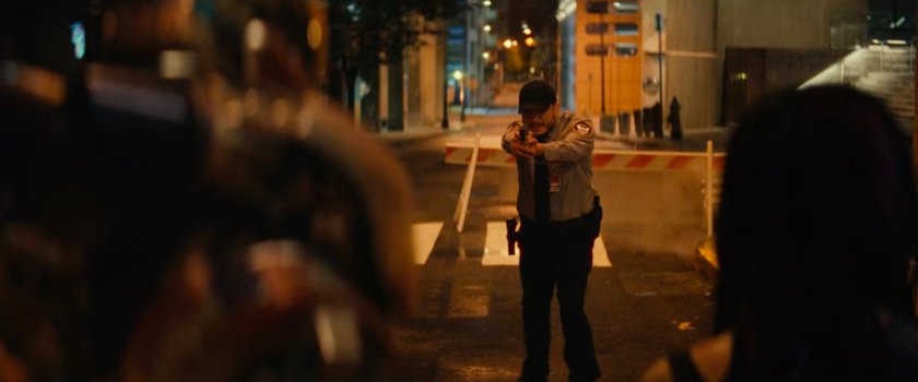 A police officer draws his weapon on Riri on the street above TNNL.