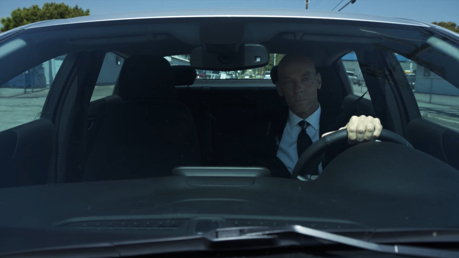 Enoch driving past an airport hangar.