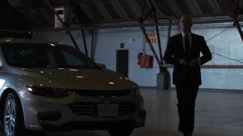 Enoch and his car in a deserted airport hangar.