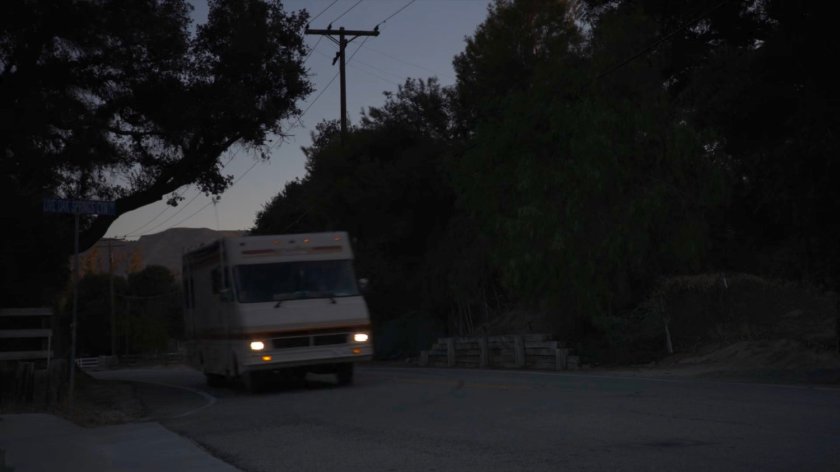 A motor home on a road at dusk.