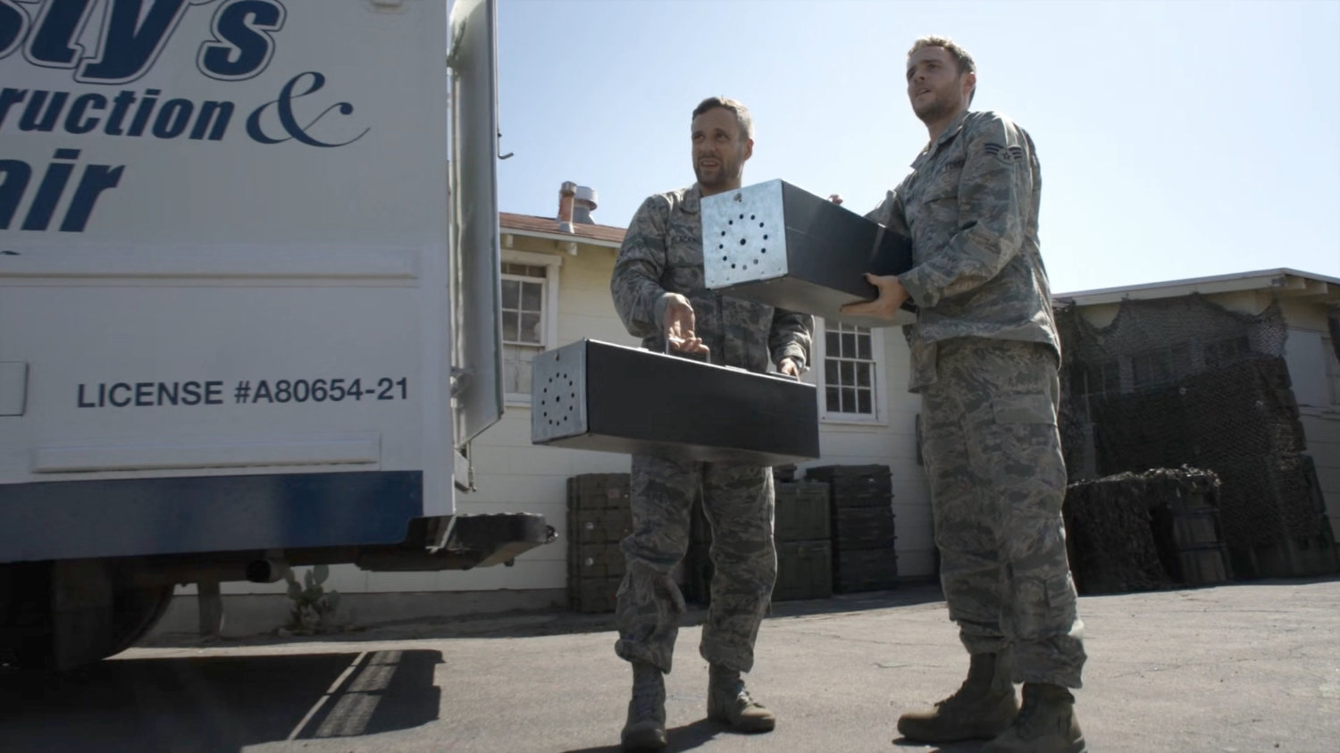 Fitz and Hunter with two metal case outside military barracks.