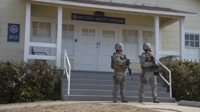 Two guards outside military airlift hangar.