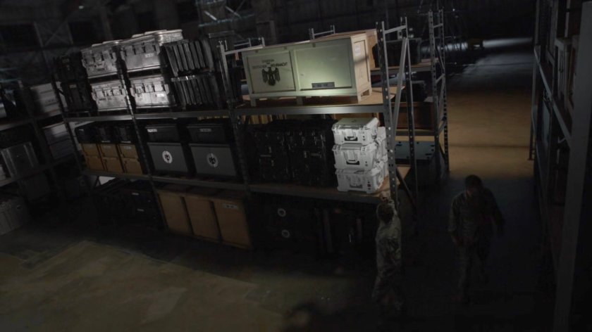 Fitz and Hunter in a military warehouse/hangar.