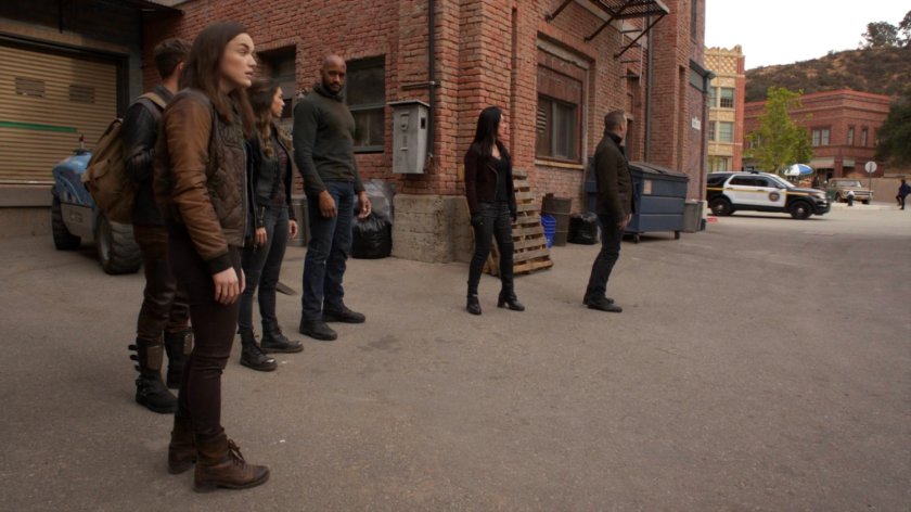 The Agents se a police car passing by an alley in River's End.