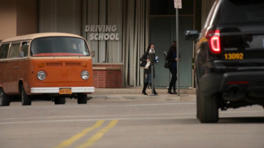 A police SUV and orange van in an intersection in River's End.