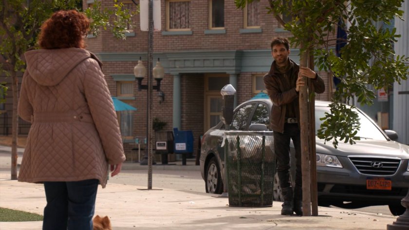 Deke holding into a tree, talking to woman in River's End.