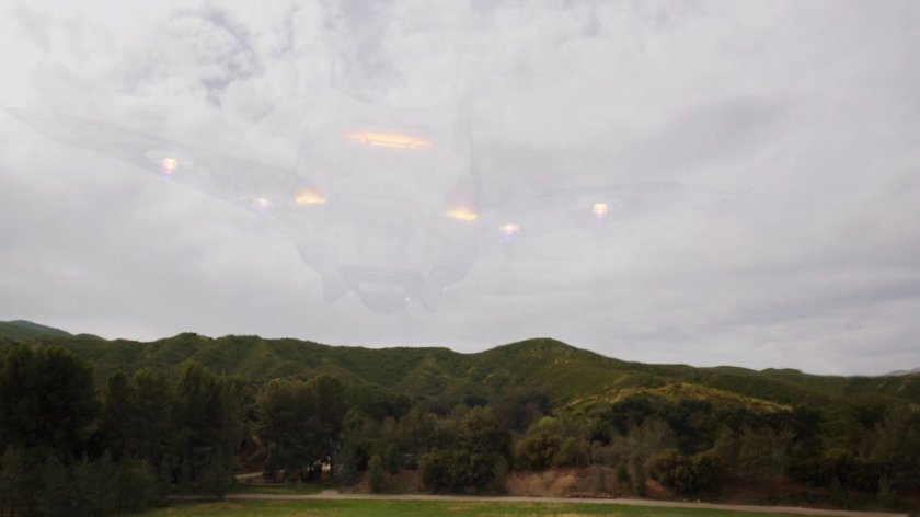 A cloaked Zephyr One flying away from a field outside River's End.