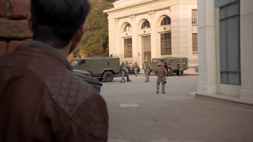 Deke peering out of an alley at soldiers in River's End.