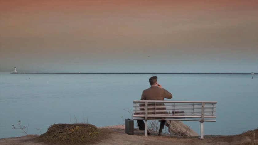 Joseph Getty on a bench overlooking a harbor.