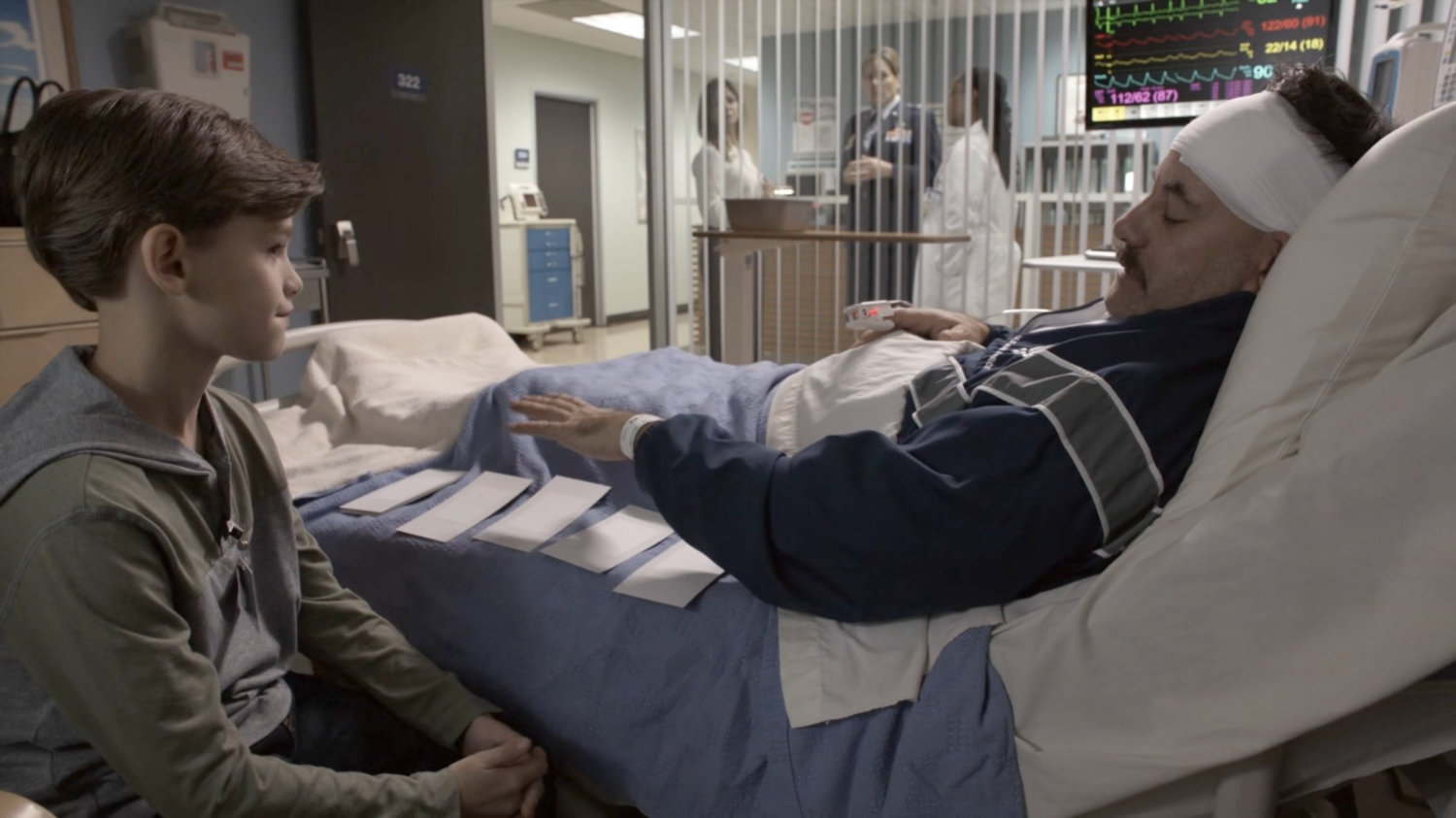 Talbot and his son in a hospital room, with his wife and General Hale speaking to Doctor Ford outside.