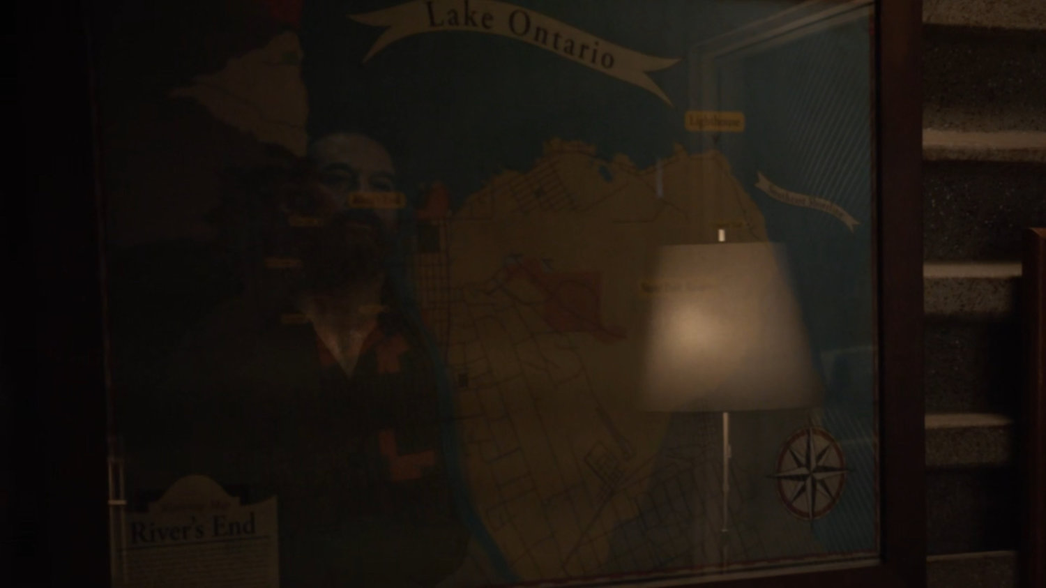 Talbot looks at a map of River's End and Lake Ontario.