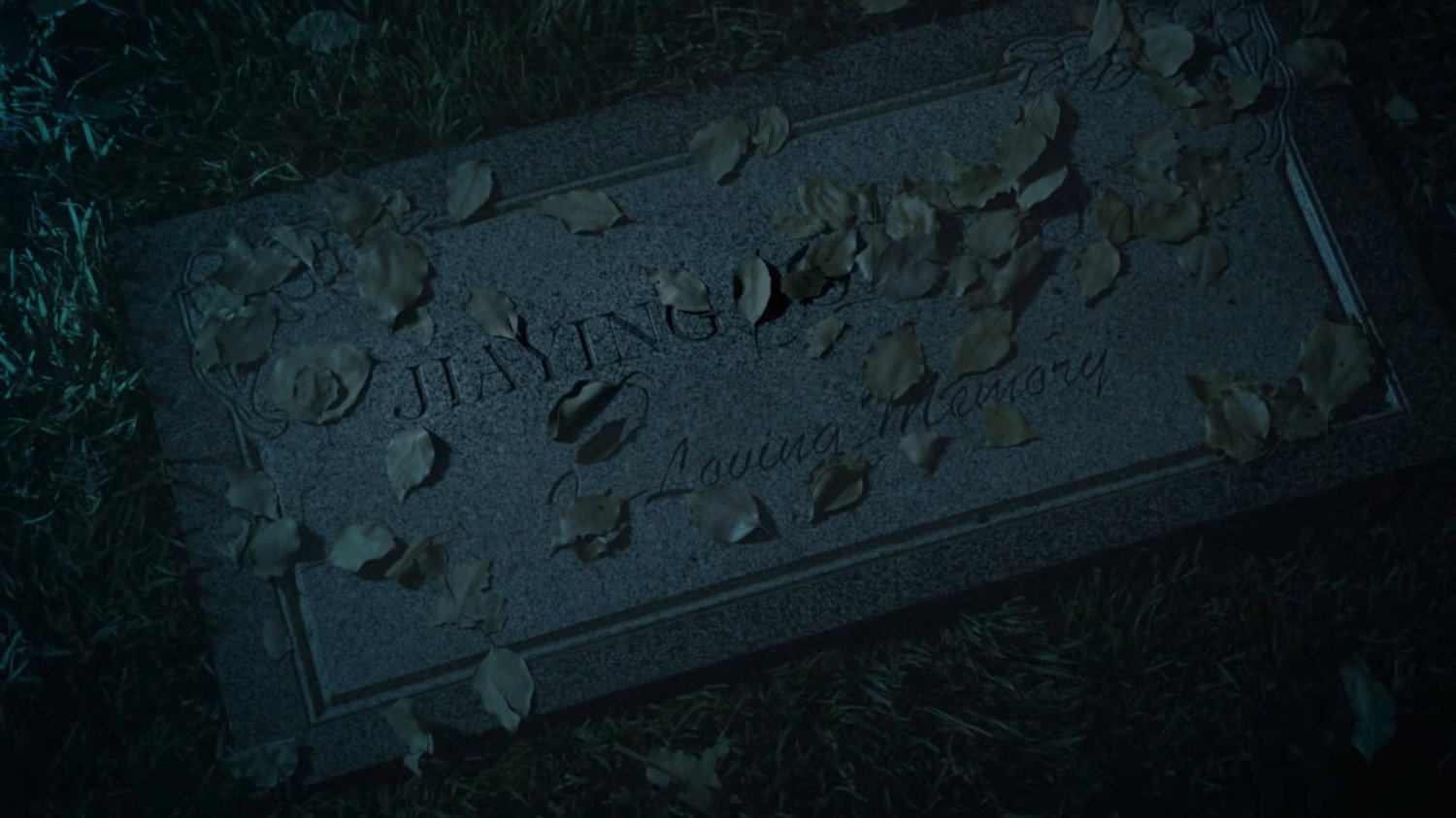 Closeup of Jiaying's grave marker in a foggy cemetery at nighttime.