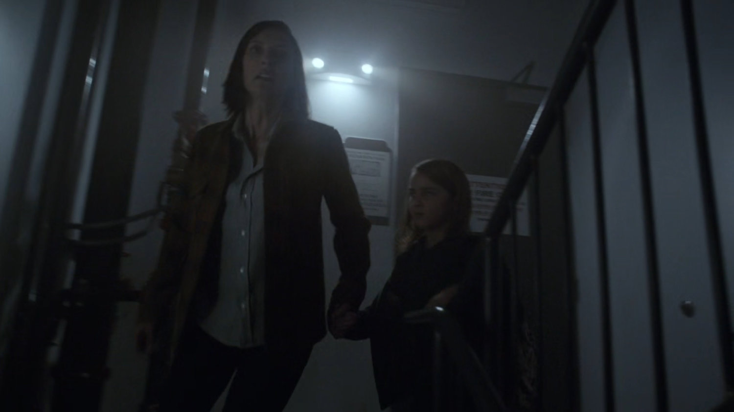 Polly and Robin descend stairs in a Chicago high rise.