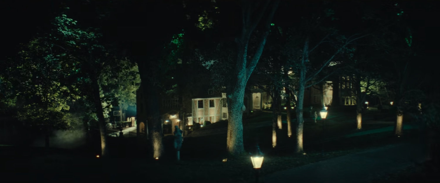 Exterior of a fancy mansion at night.