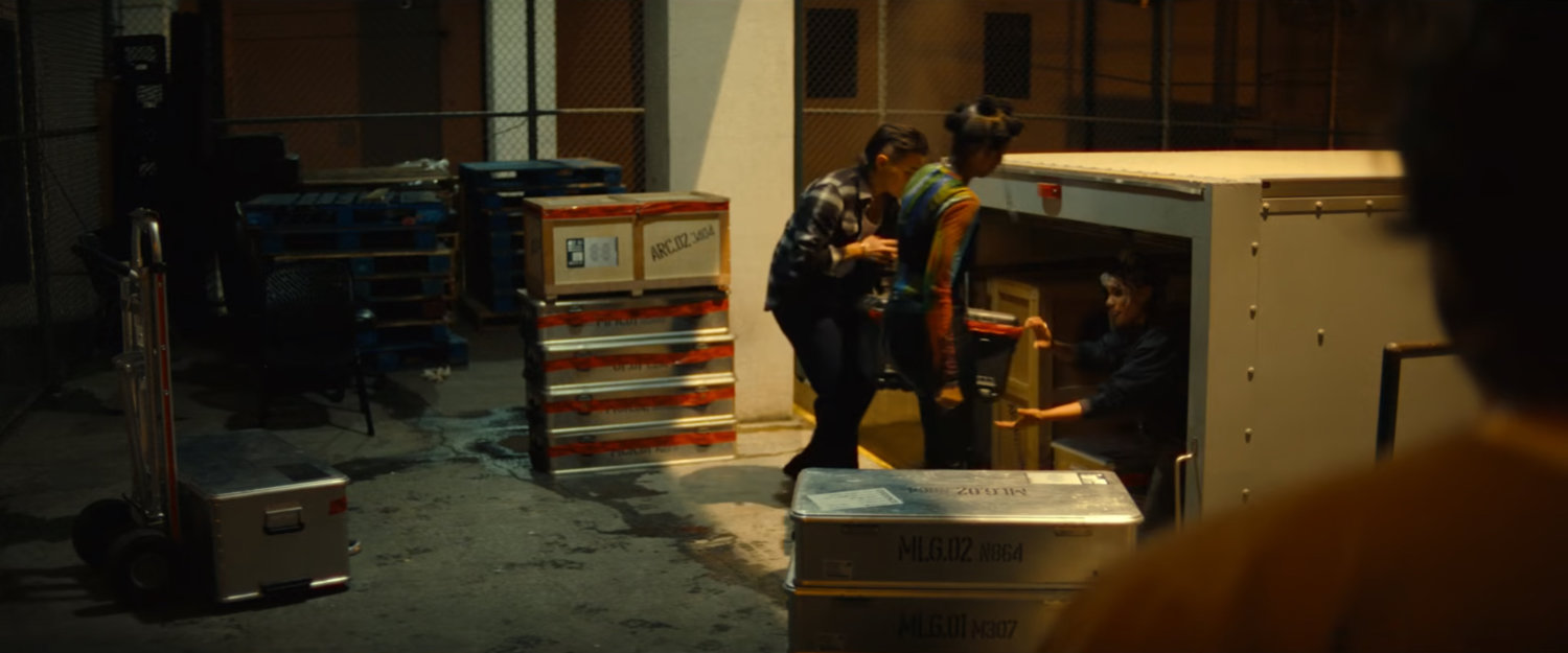 Jeri, Roz, and Clown loading Joe's gear into a van at the loading dock of Cook County Jail.