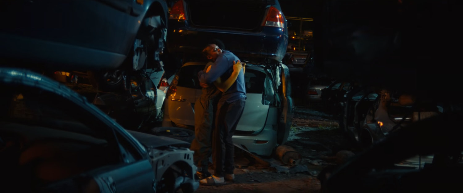 Riri hugging Xavier in a junkyard.
