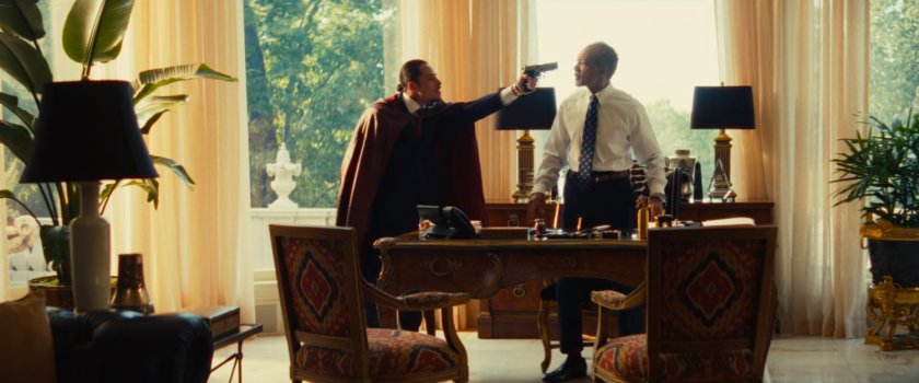 The Hood holds a gun on his father, Arthur, in a mansion.