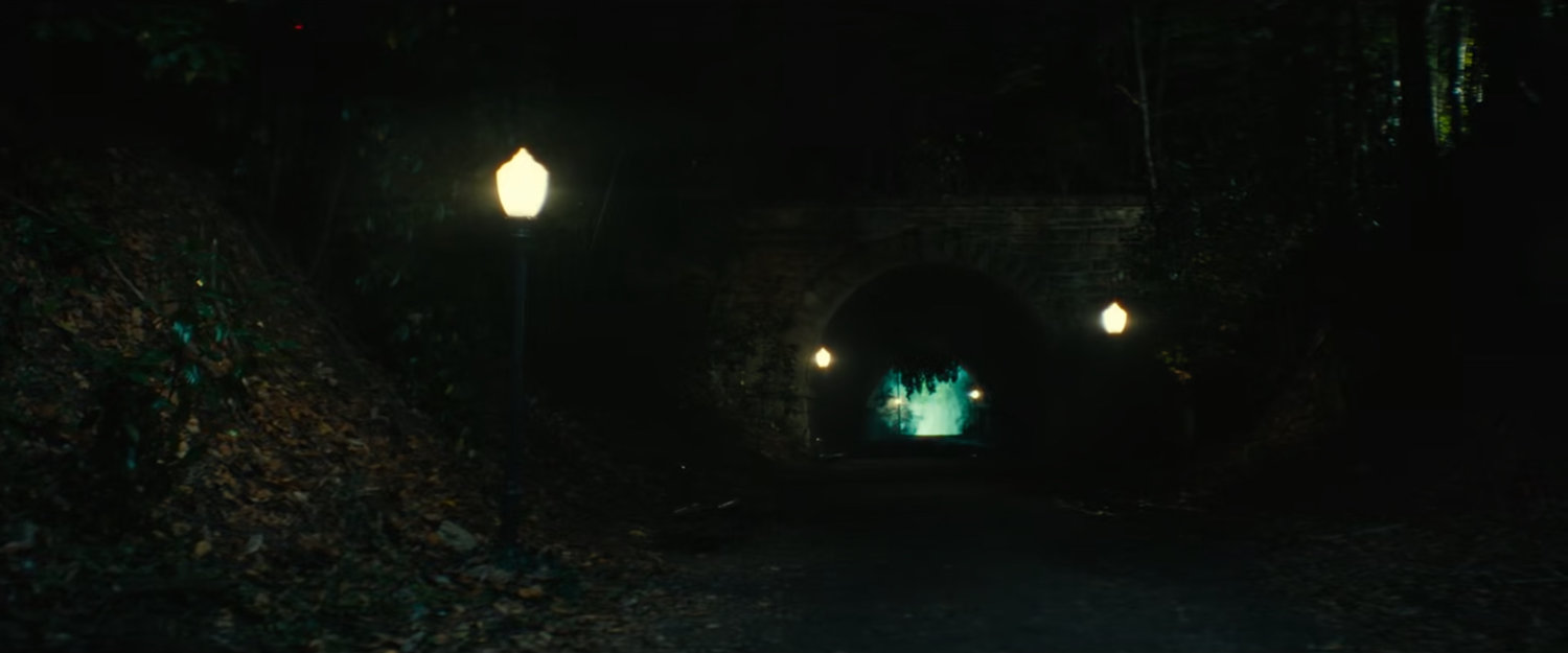 Parker runs towards an eerie tunnel outside the fancy mansion.