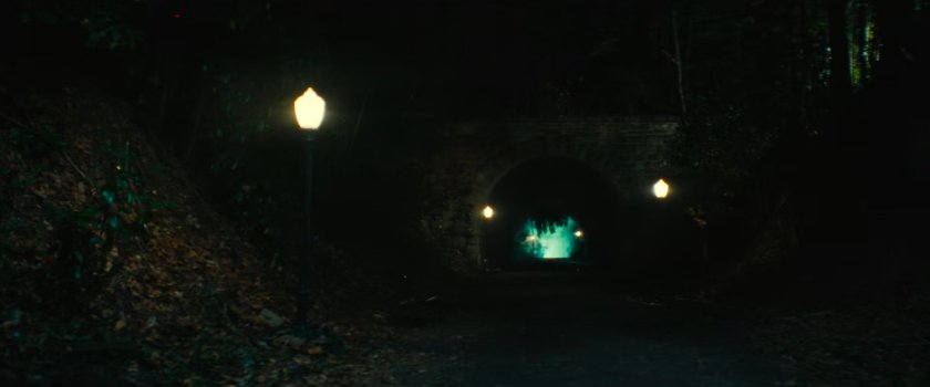 Parker runs towards an eerie tunnel outside the fancy mansion.