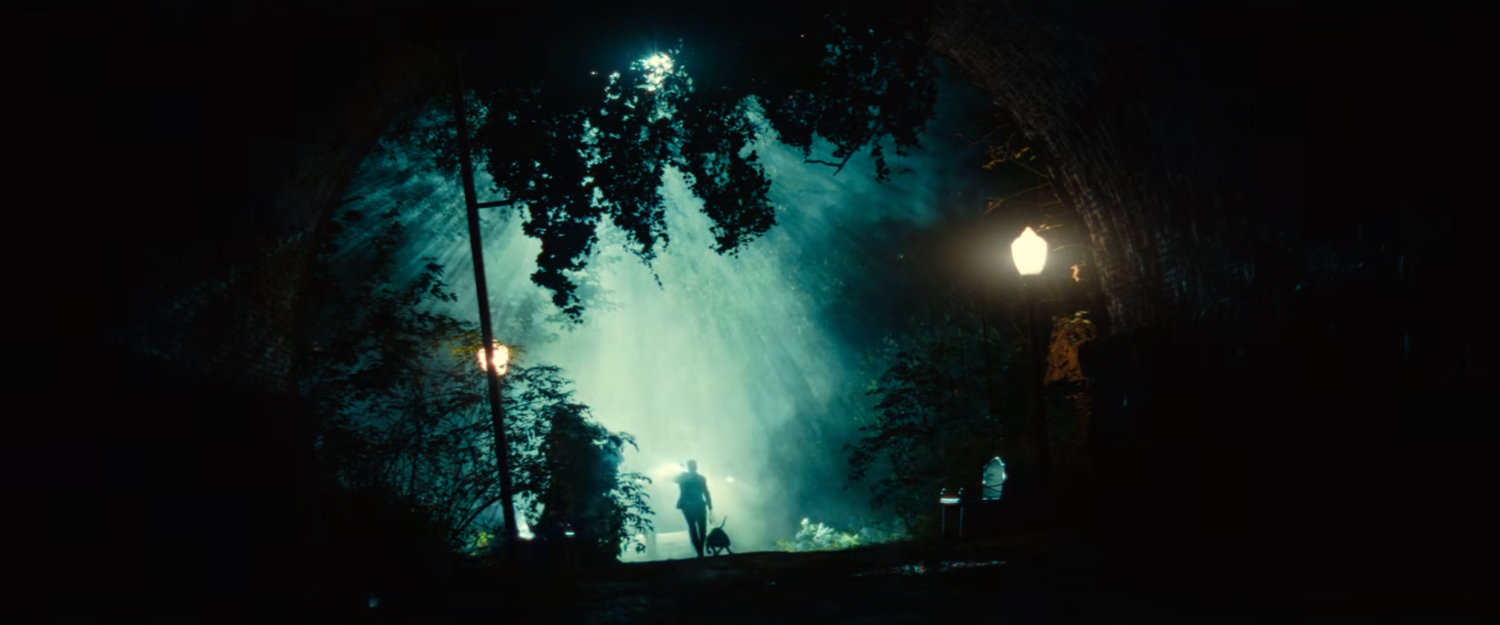 Guard with dog heading toward an eerie tunnel outside the fancy mansion.