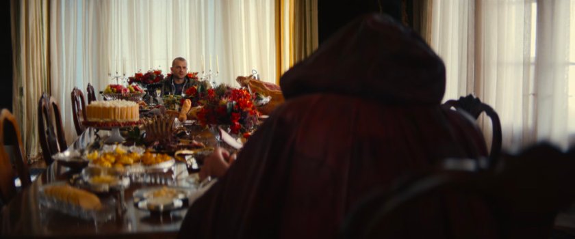 Joe at a well-laden table in a fancy mansion