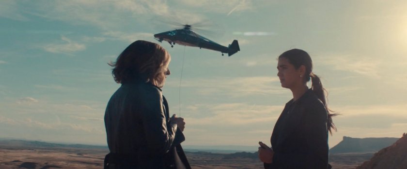 Mel and Valentina on a hill, with a helicopter in background, near the OXE Vault in Utah.